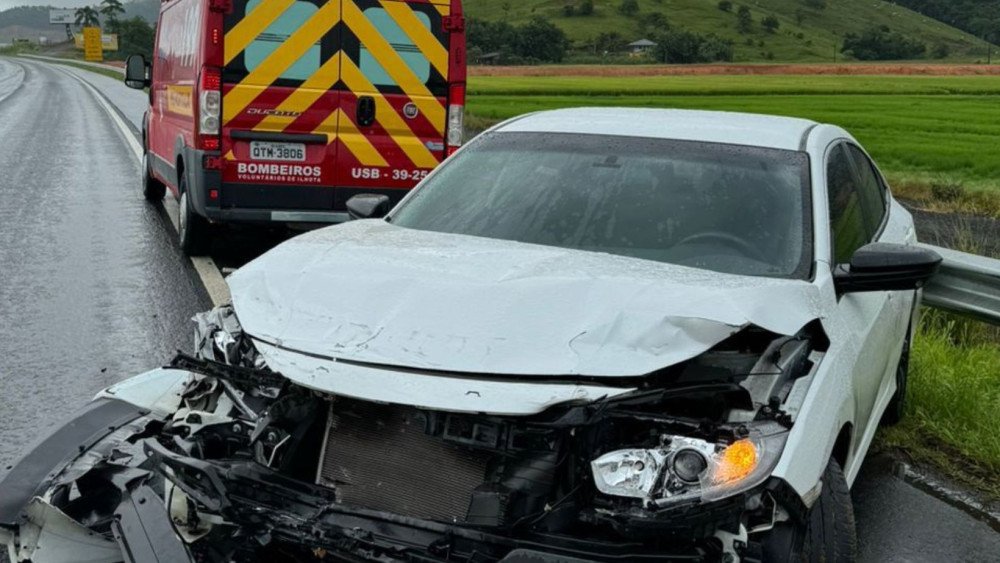 Carro bate em barreira de metal e fica entre faixa de rolamento e acostamento na BR-470